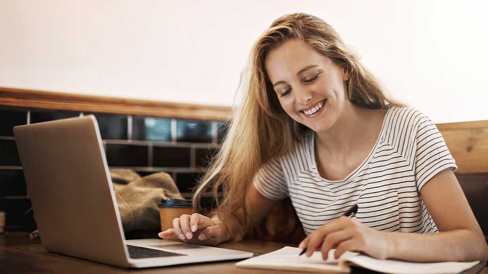 Mladá žena se věnuje studiu na notebooku a zapisuje si poznámky_02