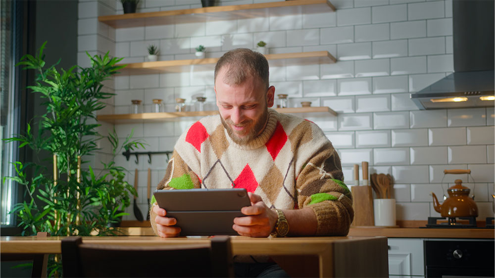 Muž u kuchyňského stolu s tabletem_04