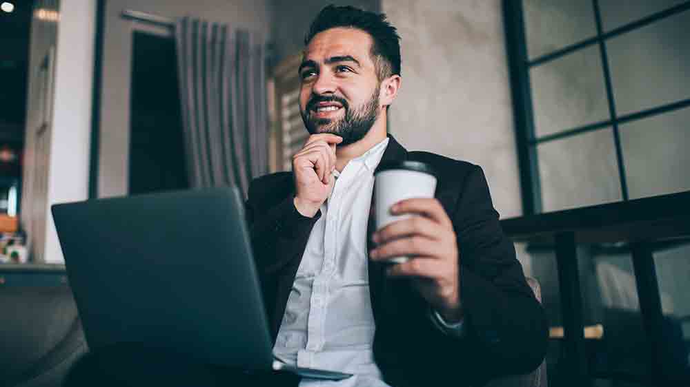 Muž sedí v kavárně a pracuje na notebooku_03