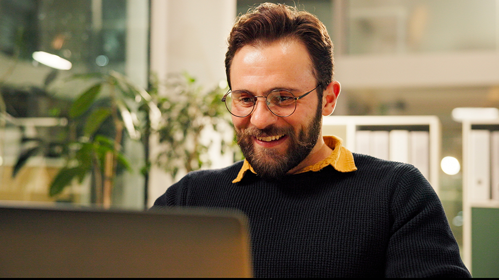 šťastný muž kouká do svého laptopu