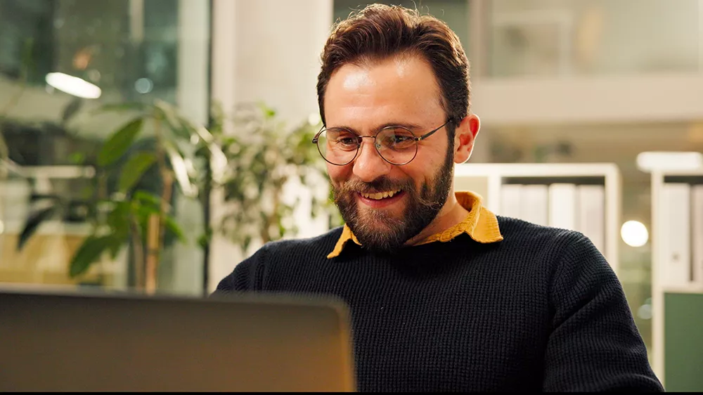 šťastný muž pozerá do svojho laptopu