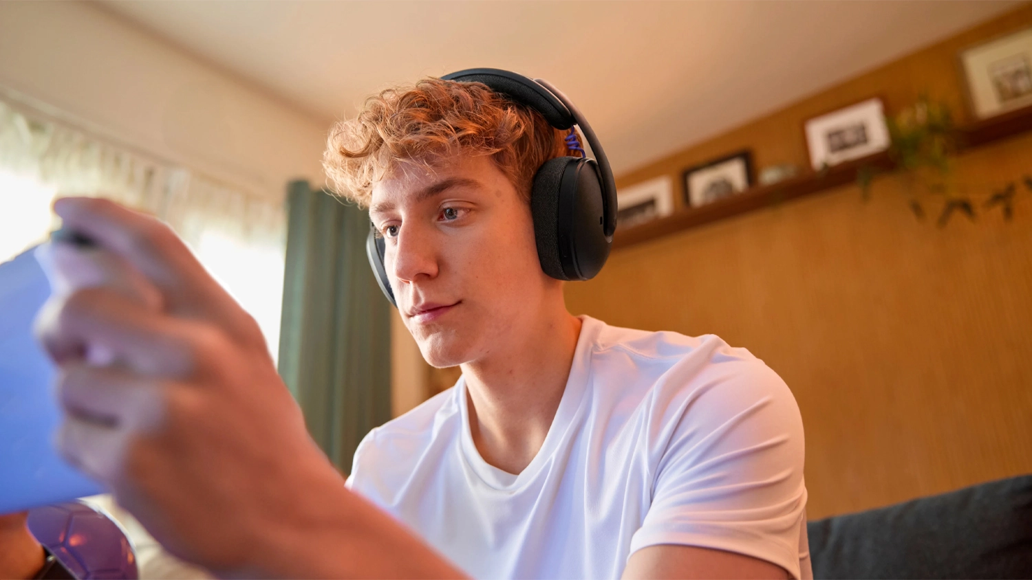 Muž hrající na konzoli s nasazenými sluchátky Logitech G325 LIGHTSPEED
