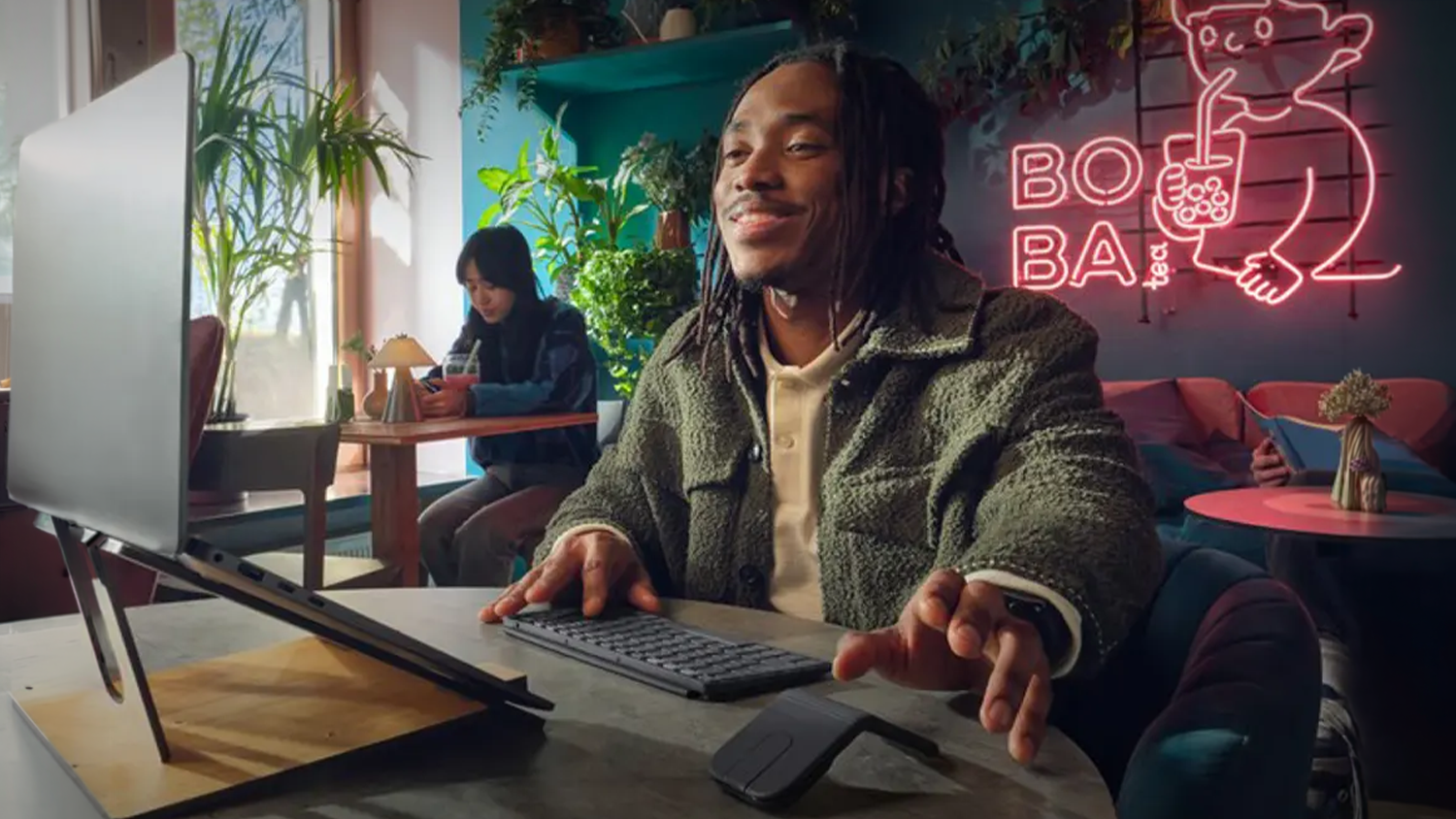 Muž v kavárně pracuje na notebooku s myší Logitech MOBI FOLD Graphite