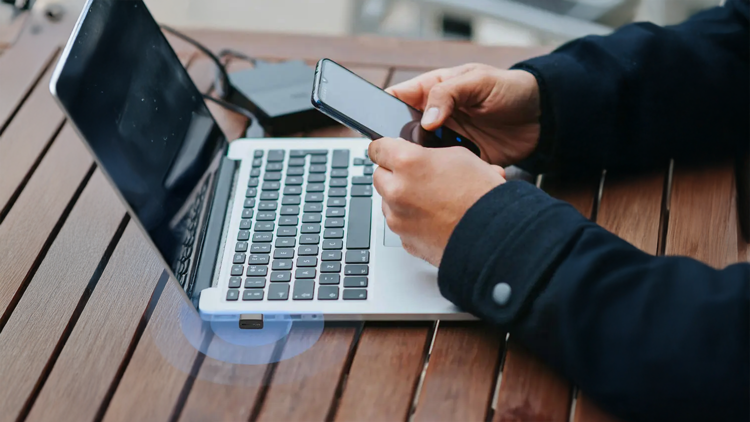 Muž pracuje na mobile a notebooku so zasunutým USB adaptérom Mercusys MA14N Nano