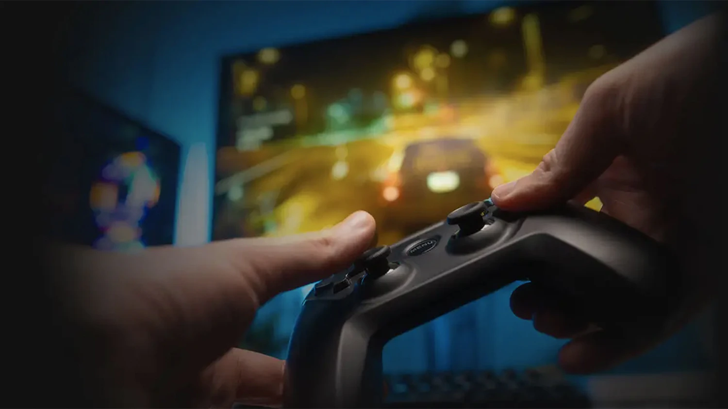 Ruce držící joystick před monitorem