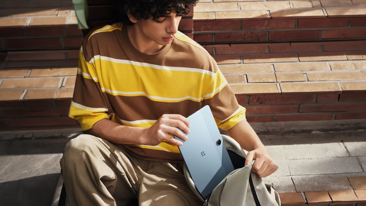 Chlapec pokl&aacute;daj&iacute;c&iacute; OnePlus Pad Lite LTE do batohu