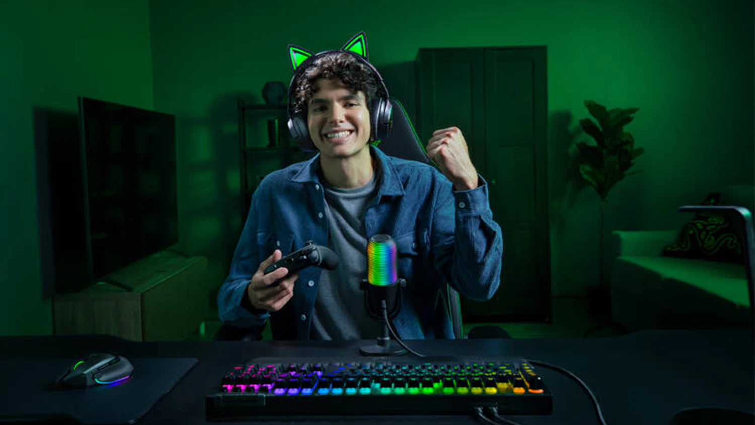 Mladík drží v ruce gamepad a hraje hru s nasazenými herními sluchátky Razer Kraken Kitty V3 Pro.