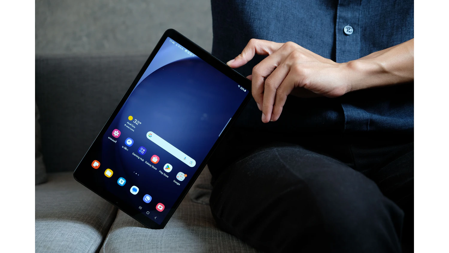 Ruka přidržuj&iacute;c&iacute; tablet Galaxy Tab S11 na gauči