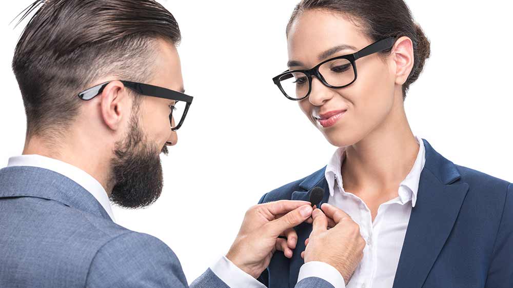 Muž připíná mikrofon na sako ženy_02