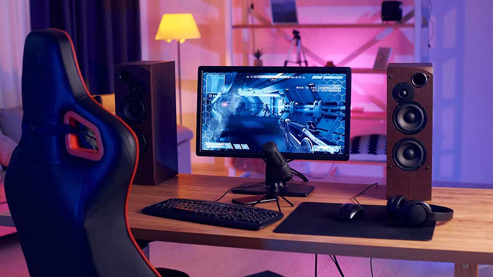 Pc stůl hráče pc her se zapnutou hrou, osvětlením, příslušenstvím a podložkou pod myš v černé barvě na stole_02