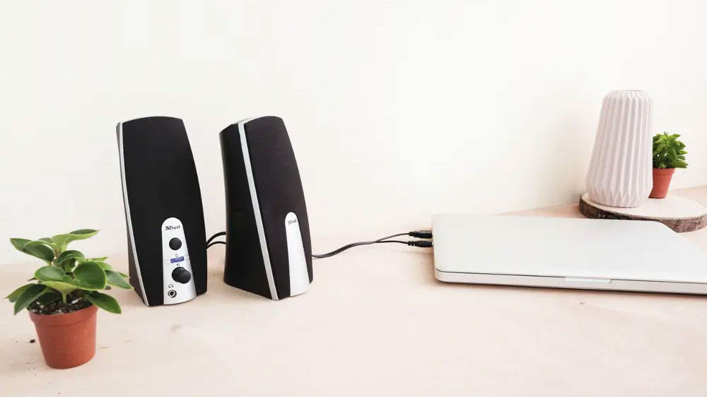Reproduktory Trust MiLa Speaker 2.0 pripojené k notebooku vedľa kvetináčov na stole_02