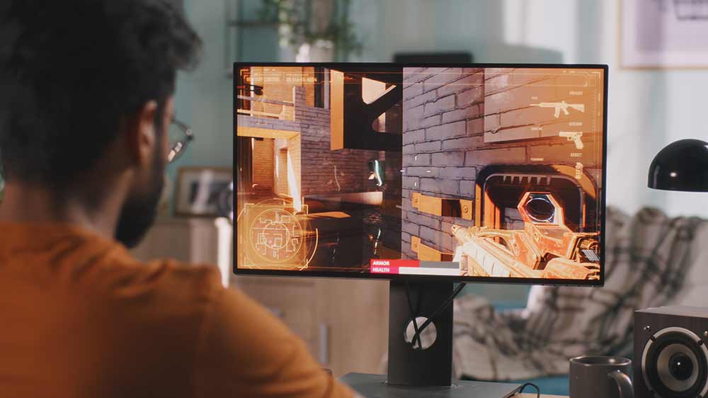 Muž hrá hru na počítači, vedľa seba má čierny reproduktor_02