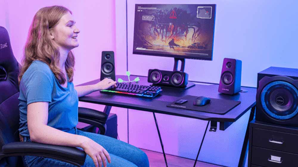 Dívka hraje hru na počítači a na stole má reproduktory Trust GXT 658 Tytan 5.1_03