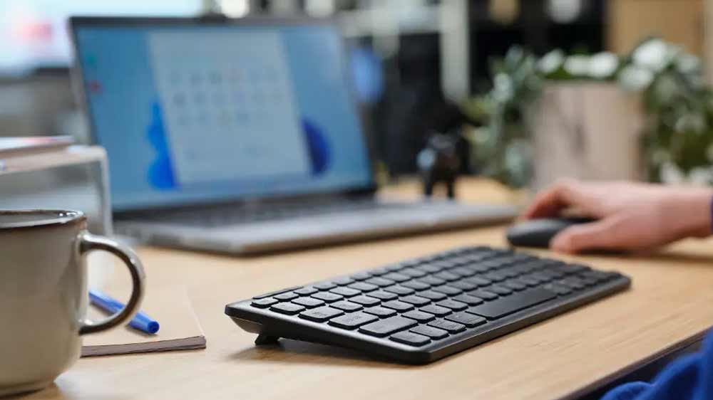 Klávesnice Trust LYRA Wireless US s nastavitelnými nožičkami na stole u notebooku_03