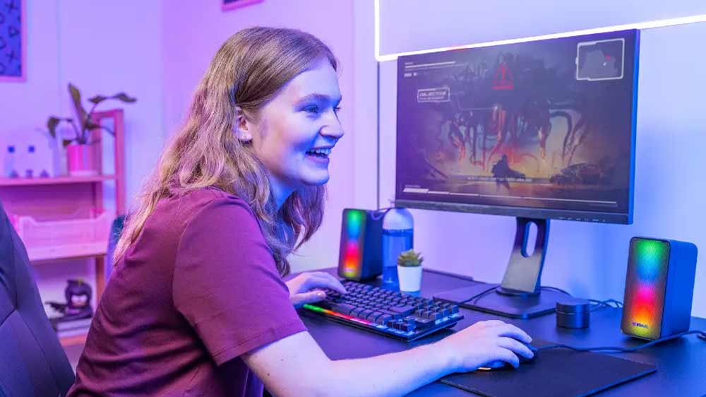 Veselá dívka hraje hru na počítači, u kterého má reproduktory Trust GXT 611 Wezz 2.0 s barevným podsvícením_03