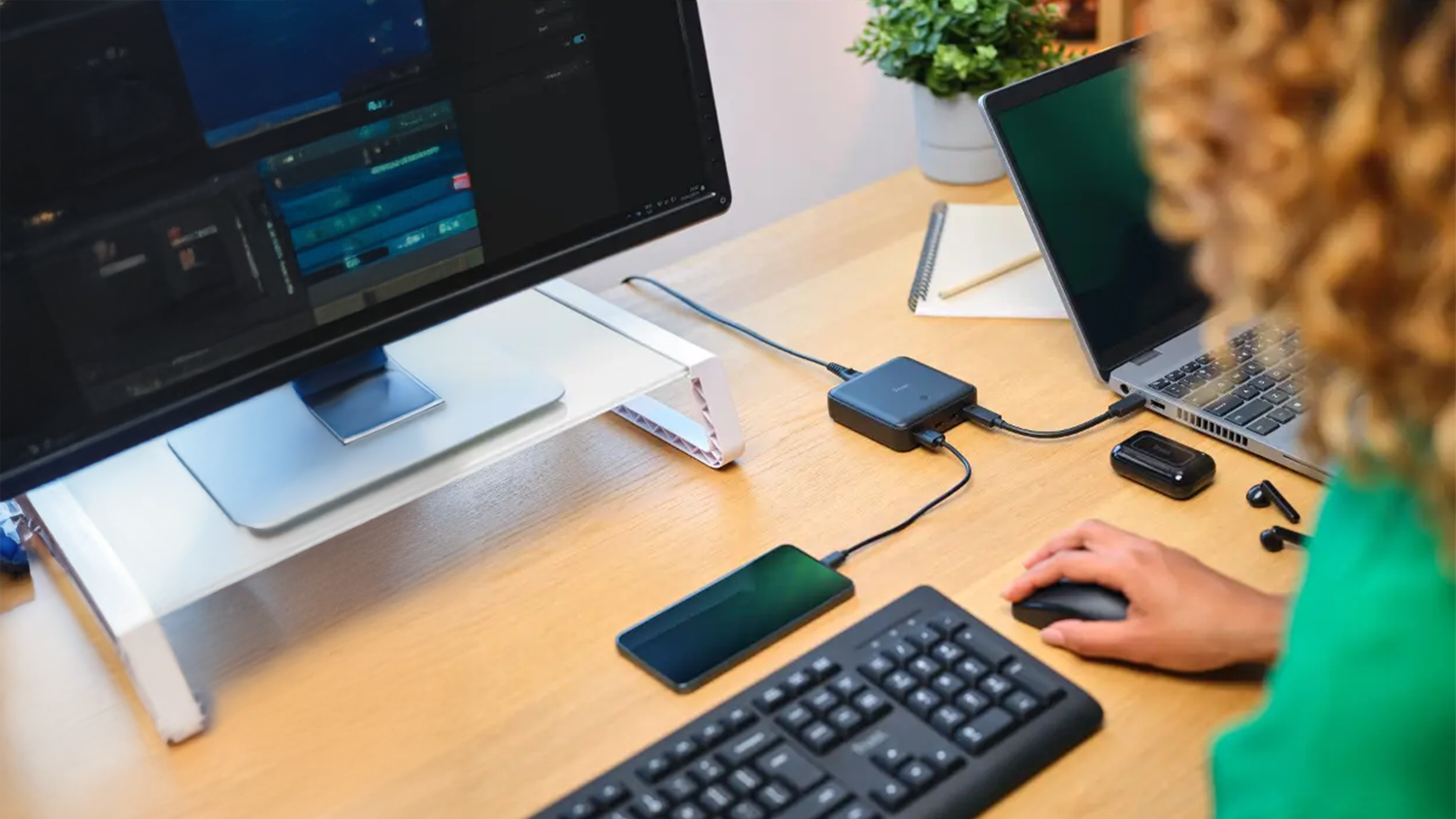 Žena pracuje na PC a na adapt&eacute;ru Trust Maxo USB-C/USB-A 100W m&aacute; zapojen&yacute; notebook a mobil