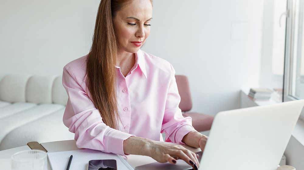Žena v růžové košili pracuje na notebooku_02