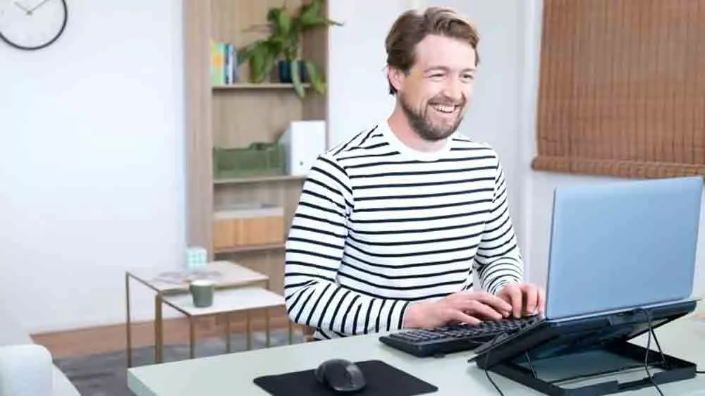 Muž pracujúci na notebooku položenom na chladiacom stojane TRUST_02