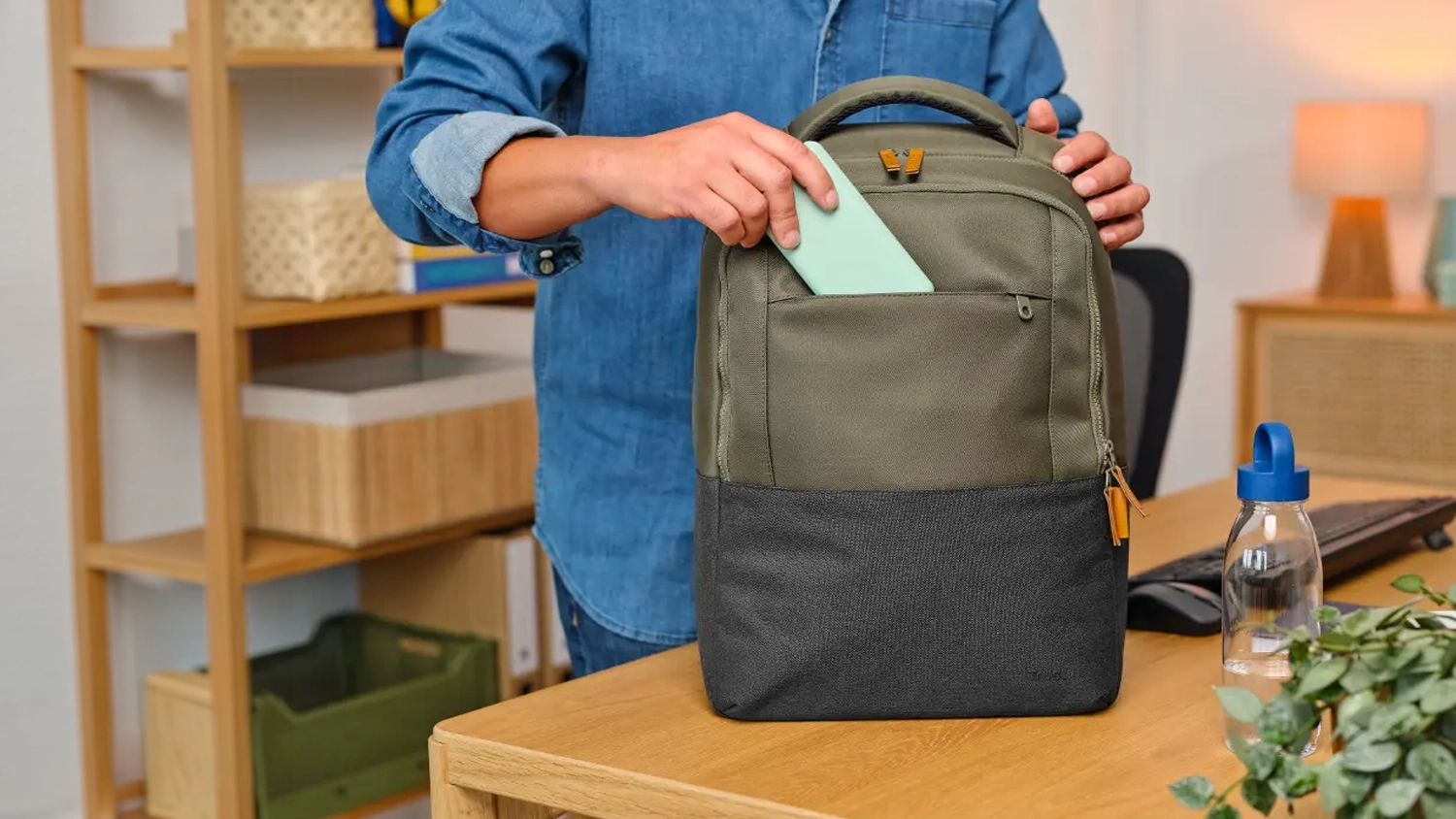 Muž vkladá mobil do batohu pre notebook Trust Lisboa Backpack 16
