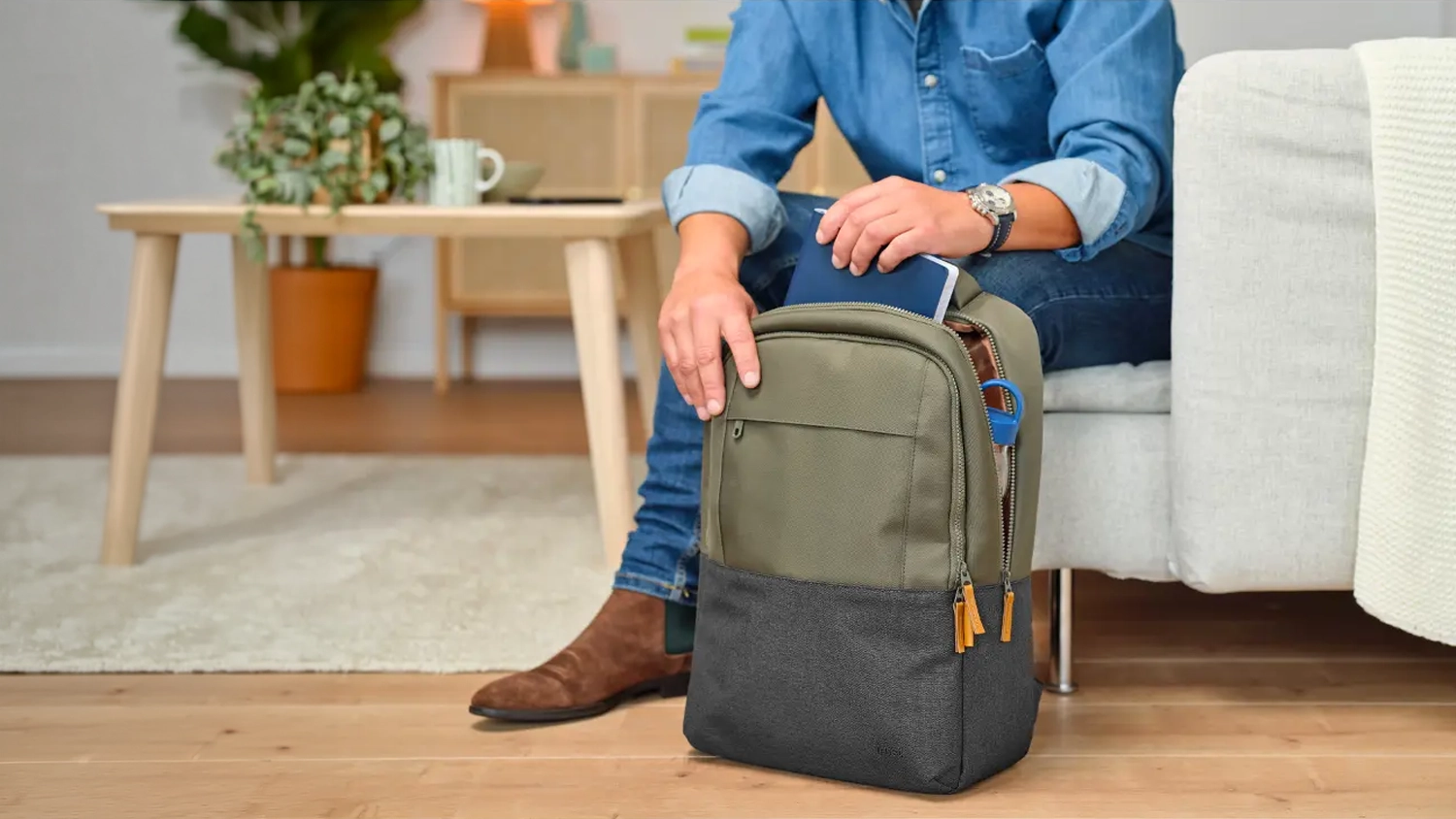 Muž sedí a vkladá zošit do batohu pre notebook Trust Lisboa Backpack 16