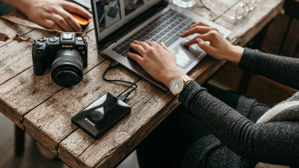 Mladá žena v kavárně přesouvá soubory z notebooku na externí HDD_02