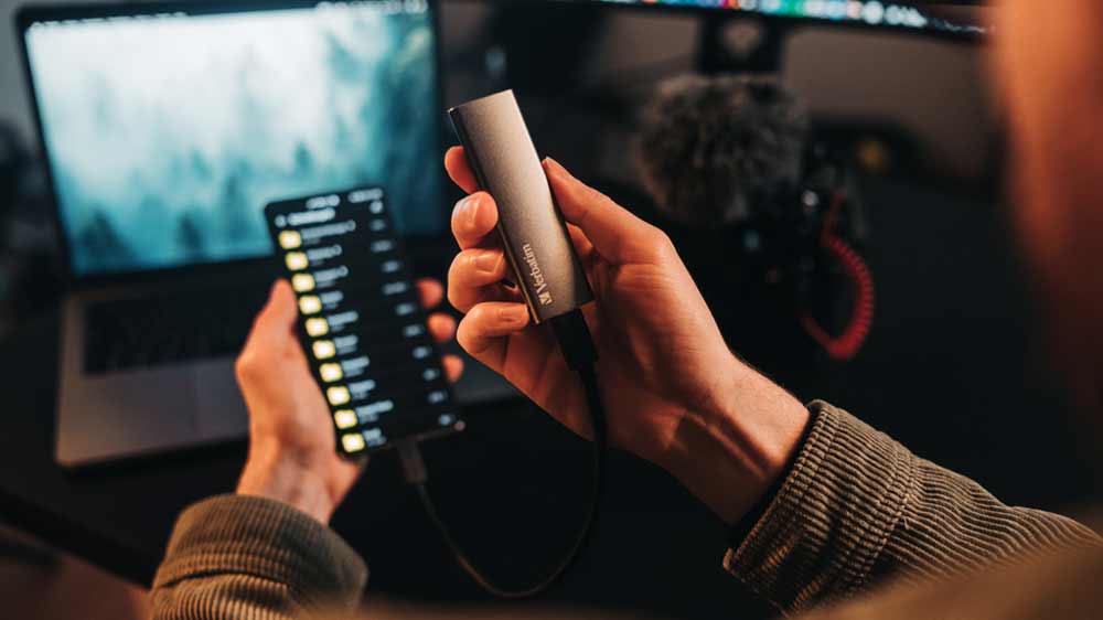 Muž držící externí SSD disk Verbatim VX500 připojený k telefonu_02