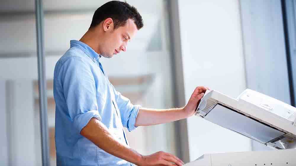 Mlad&yacute; muž stojaci pri tlačiarni_02