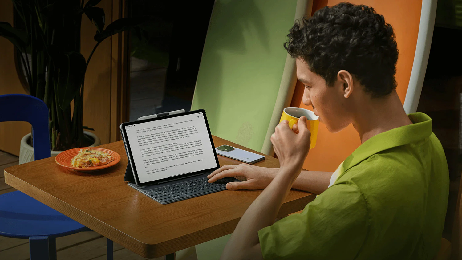 Chlapec pop&iacute;jej&iacute;c&iacute; čaj pracuje na tabletu postaven&eacute;m v pouzdru s kl&aacute;vesnic&iacute;