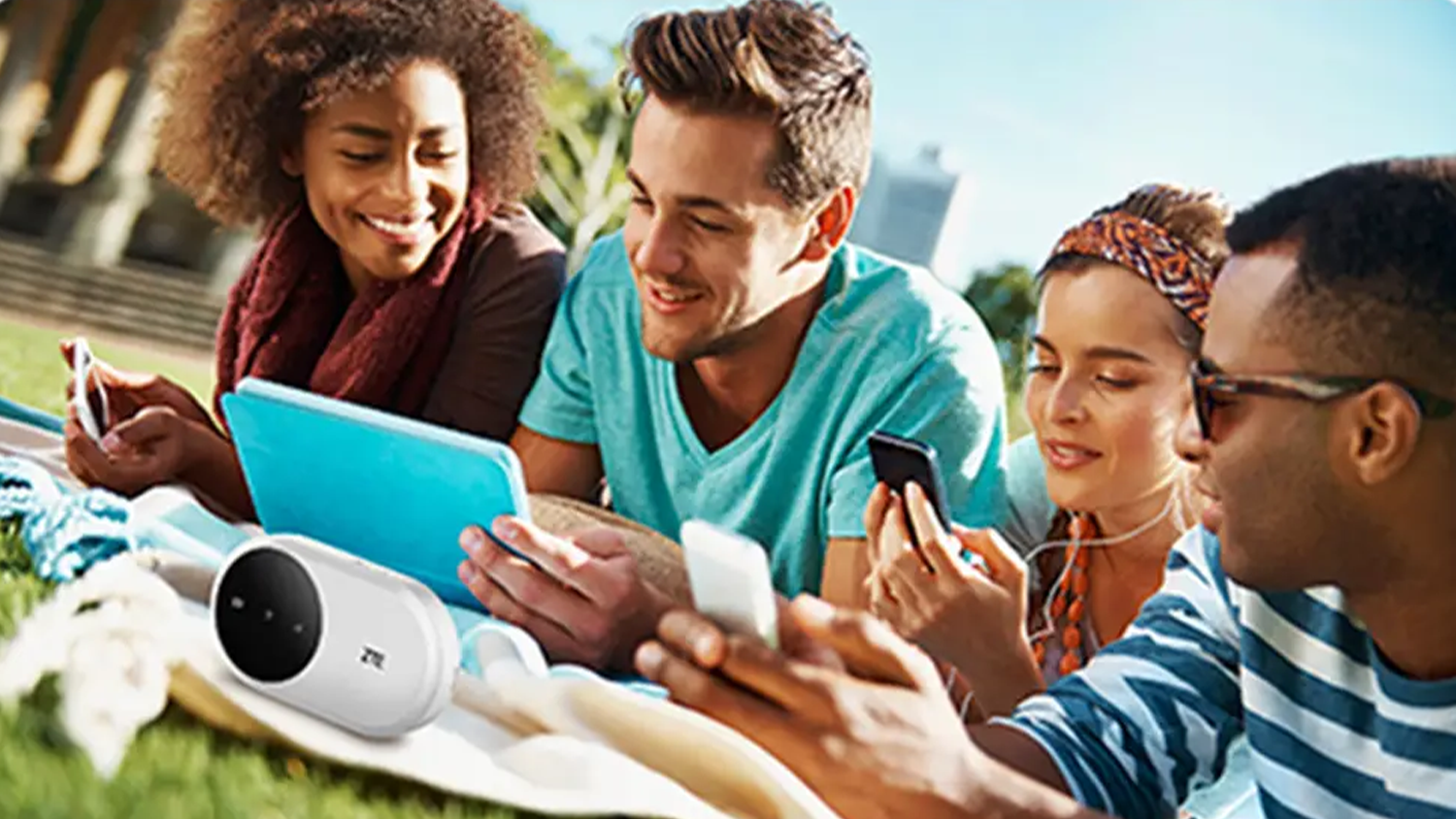 Skupina lidí leží v parku a koukají na videa s připojením na Wi-Fi router ZTE U10N 4G