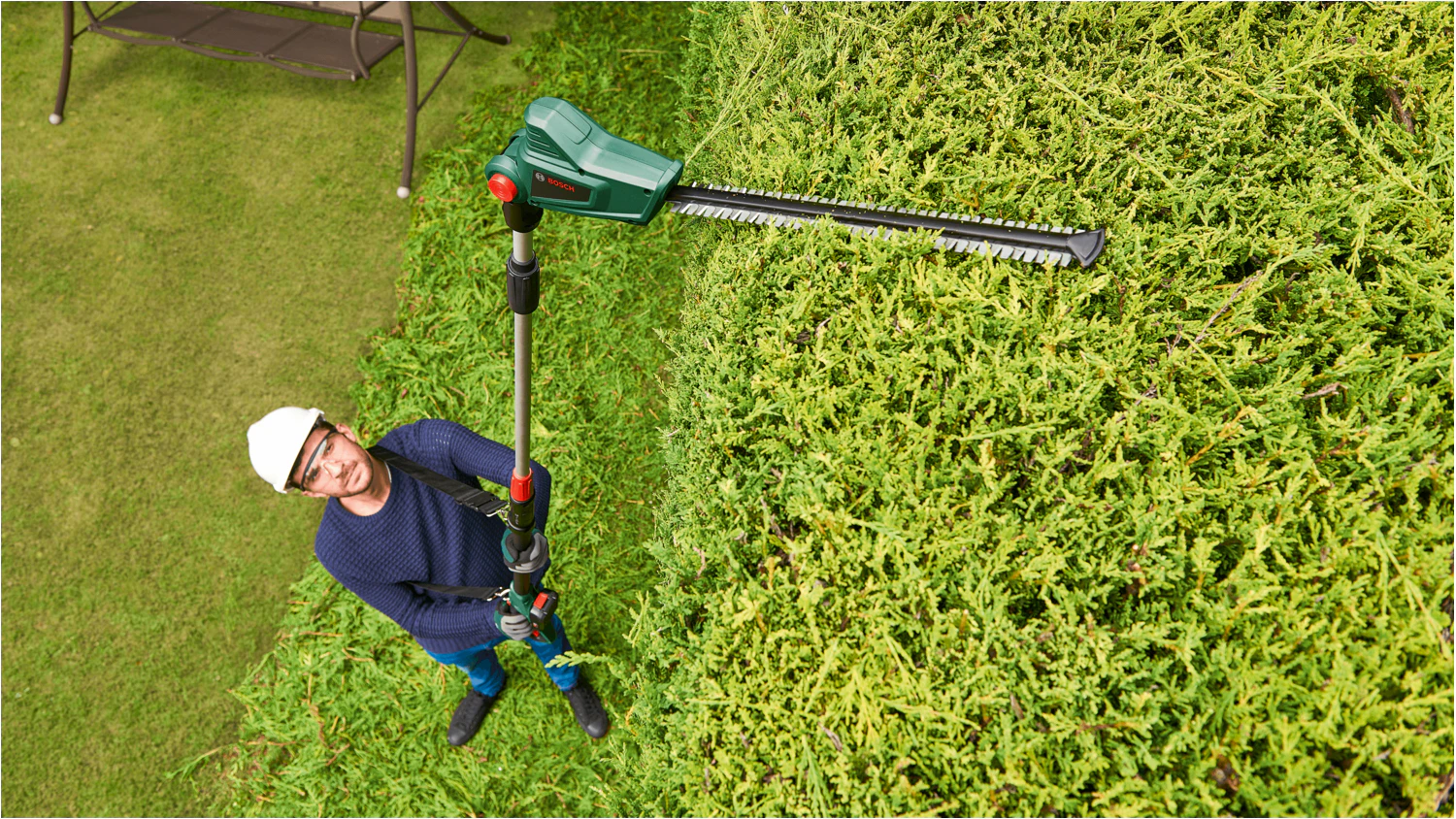 Muž používající akumulátorové nůžky na živý plot Bosch UniversalHedgePole 18 / pohled shora