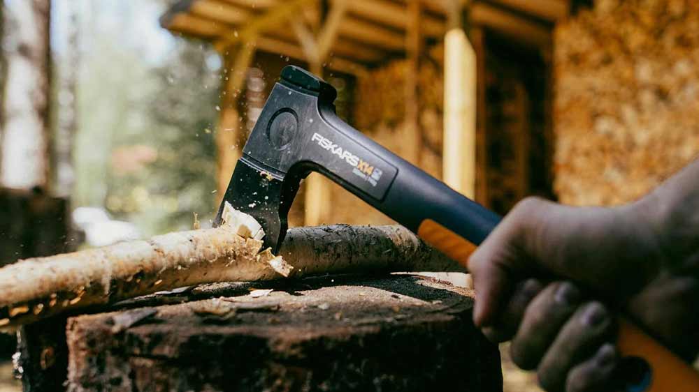 Muž seká vetvu s univerzálnou sekerou Fiskars X18