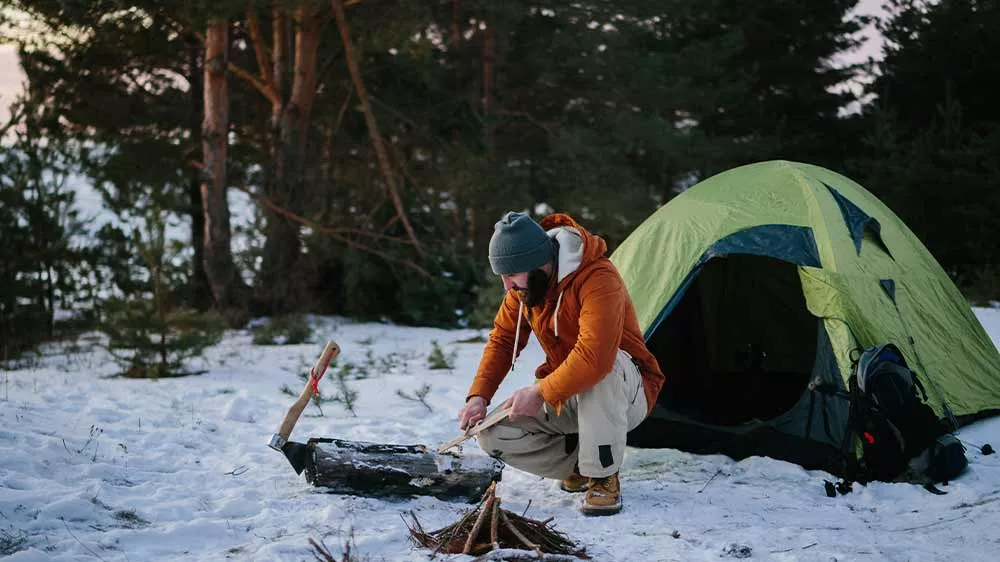 Muž v prírode pripravuje nožom triesky