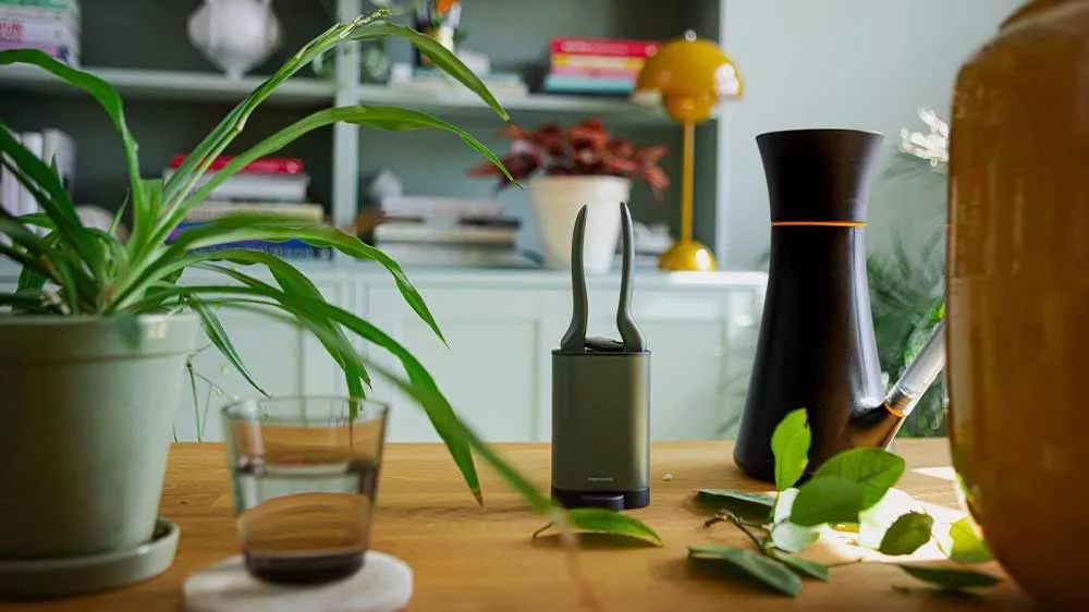 Záhradné nožnice Fiskars Plant Care na stole vedľa izbovej rastliny