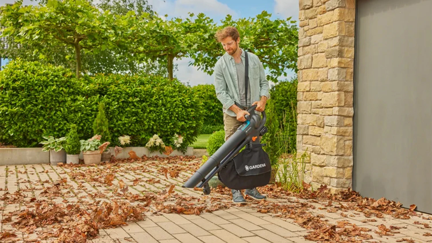 Muž při vysávání listí s vysavačem Gardena PowerJetCollect 18V