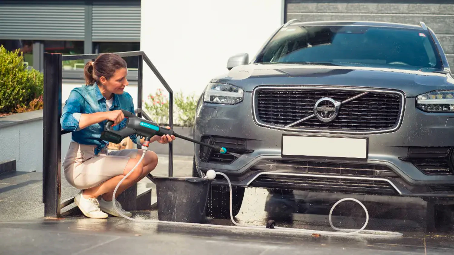 Žena um&yacute;vaj&iacute;c&iacute; spodek auta s akumul&aacute;torov&yacute;m středotlak&yacute;m čističem Gardena AquaClean 24/18V P4A