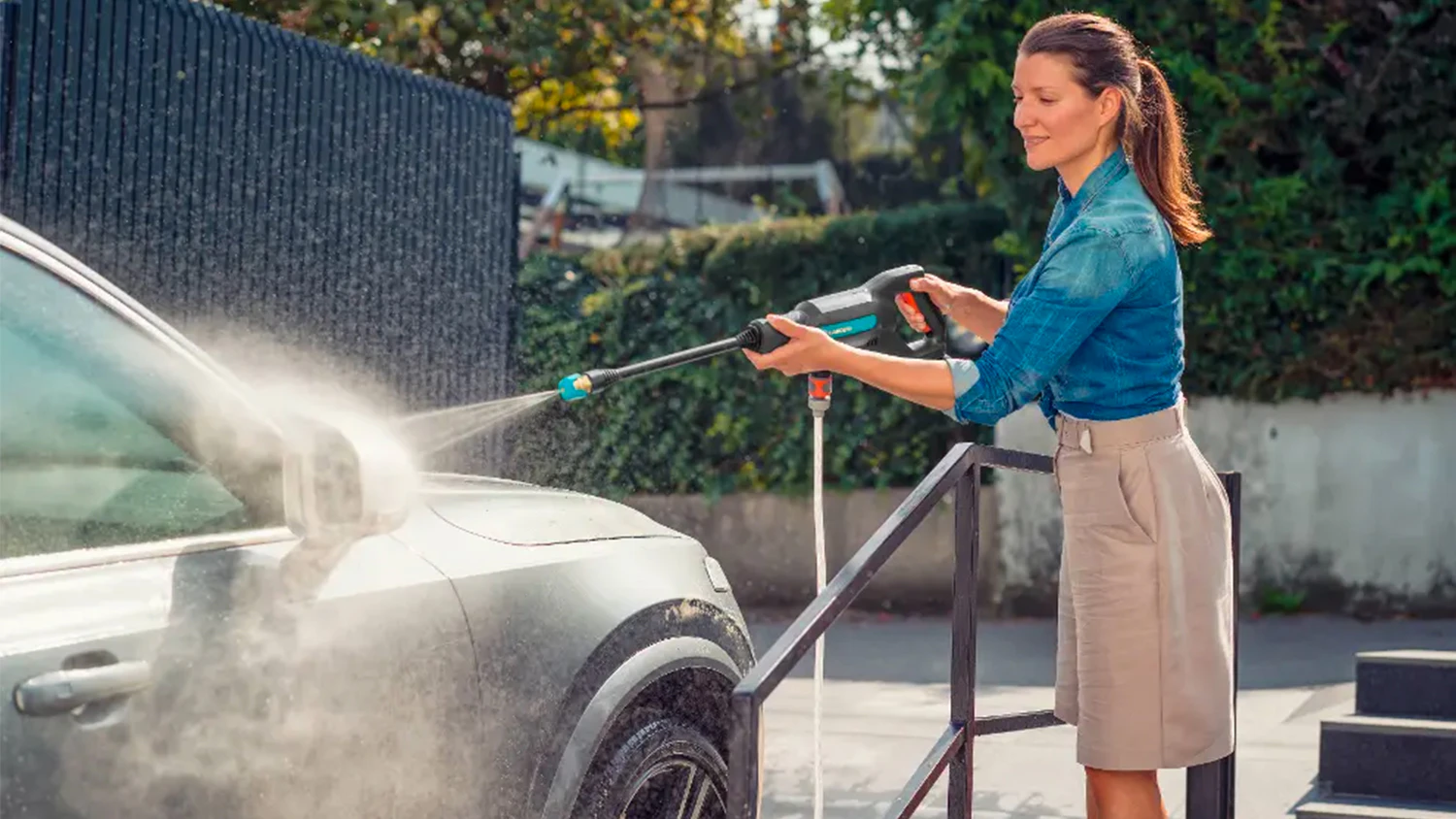 Žena um&yacute;vaj&iacute;c&iacute; auto s akumul&aacute;torov&yacute;m středotlak&yacute;m čističem Gardena AquaClean 24/18V P4A