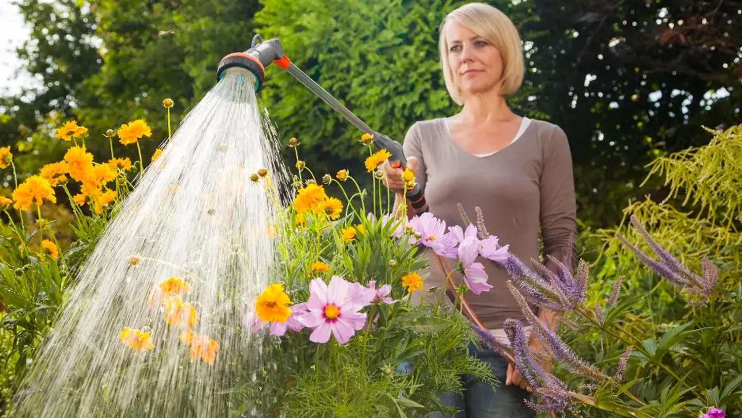 Žena zal&eacute;v&aacute; z&aacute;hon pomoc&iacute; zavlažovac&iacute; tyče Gardena