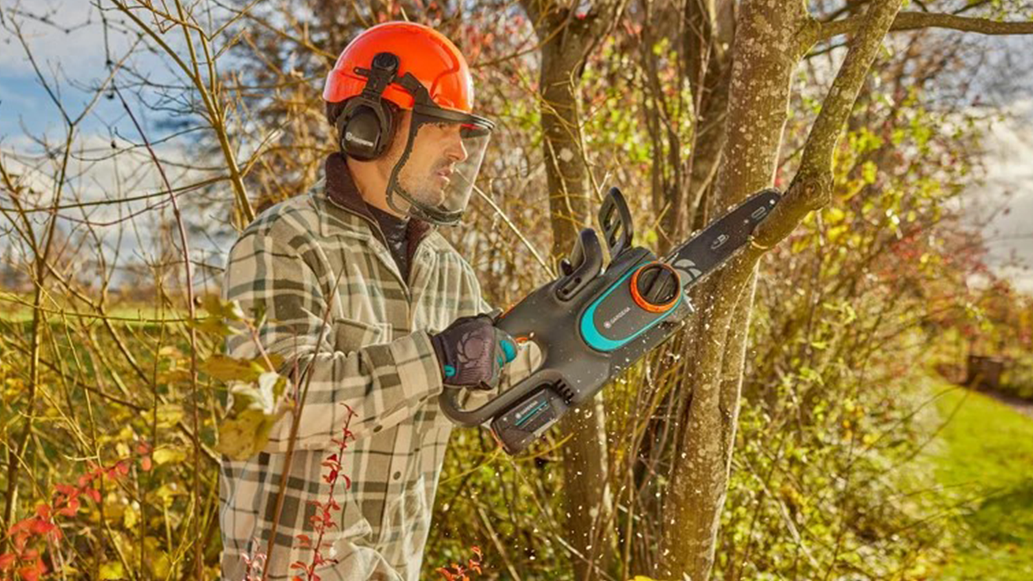 Muž řeže větve aku řetězovou pilou PowerSaw Gardena PowerSaw 250/18V P4A
