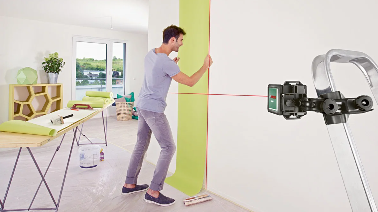 Muž lepí tapety za pomoci laseru Bosch Quigo