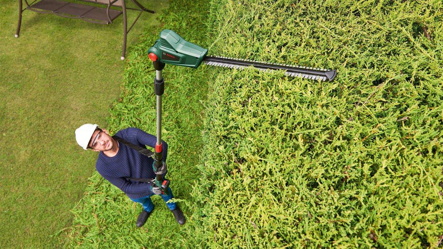 Muž používající akumulátorové nůžky na živé ploty Bosch Universal HedgePole 18