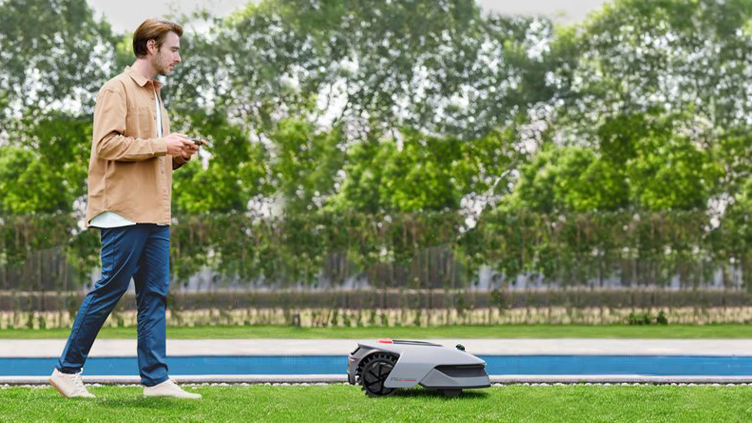 Muž používá robotickou sekačku s pomocí aplikace