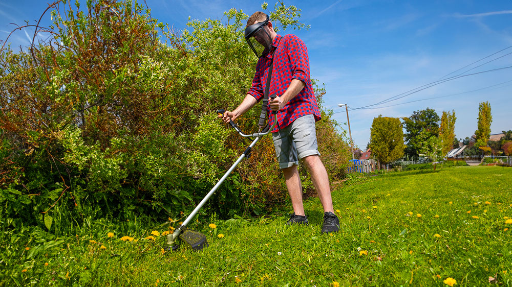Muž kos&iacute; tr&aacute;vu v kr&iacute;koch krovinorezom Fieldmann _03