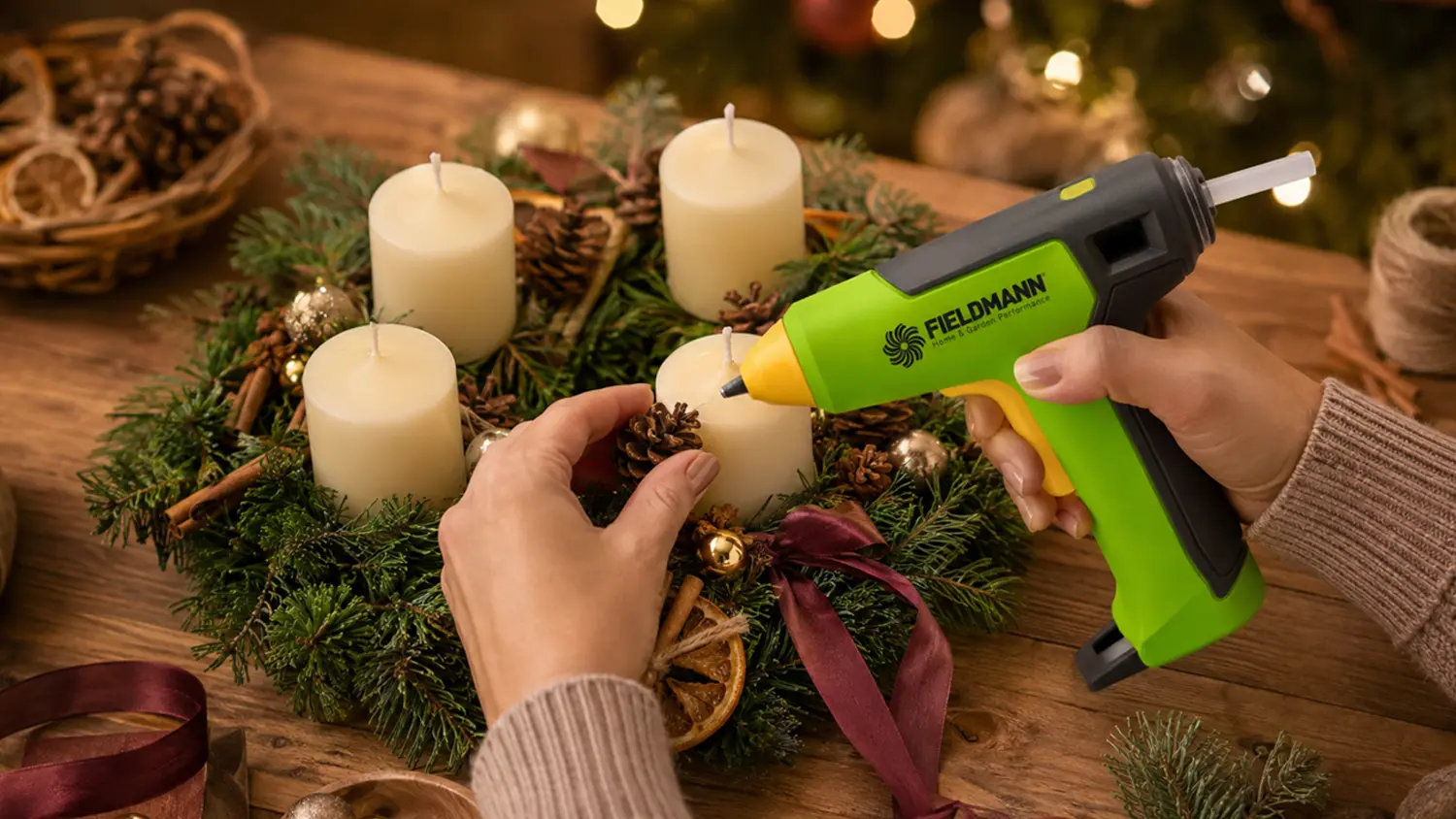 Ženské ruce zdobí adventní věnec tavnou pistolí Fieldmann FDTP 2206-A.