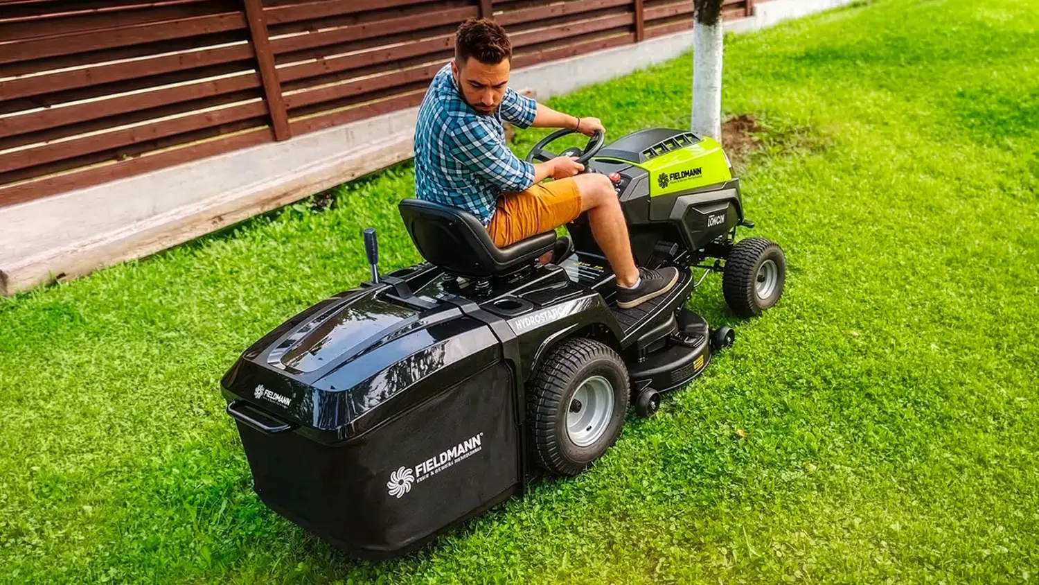 Muž jede na zahradním traktoru Fieldmann FZTR 8630-B