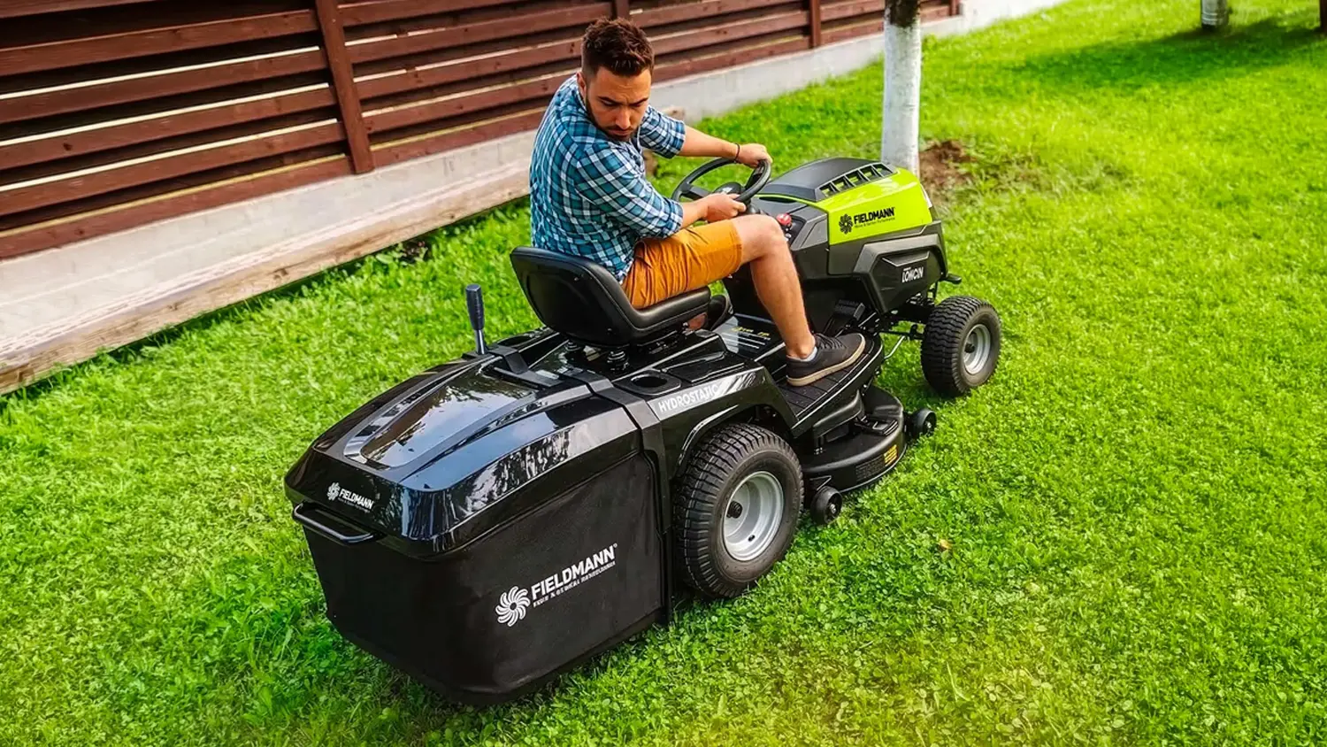 Muž jede na zahradním traktoru Fieldmann FZTR 9840-B