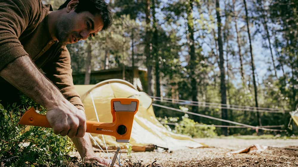 Muž zatlouká kolíky univerzální sekerou Fiskars X13_02
