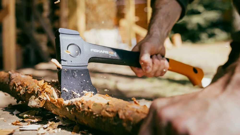 Muž seká dřevo s univerzální sekerou Fiskars X18_02