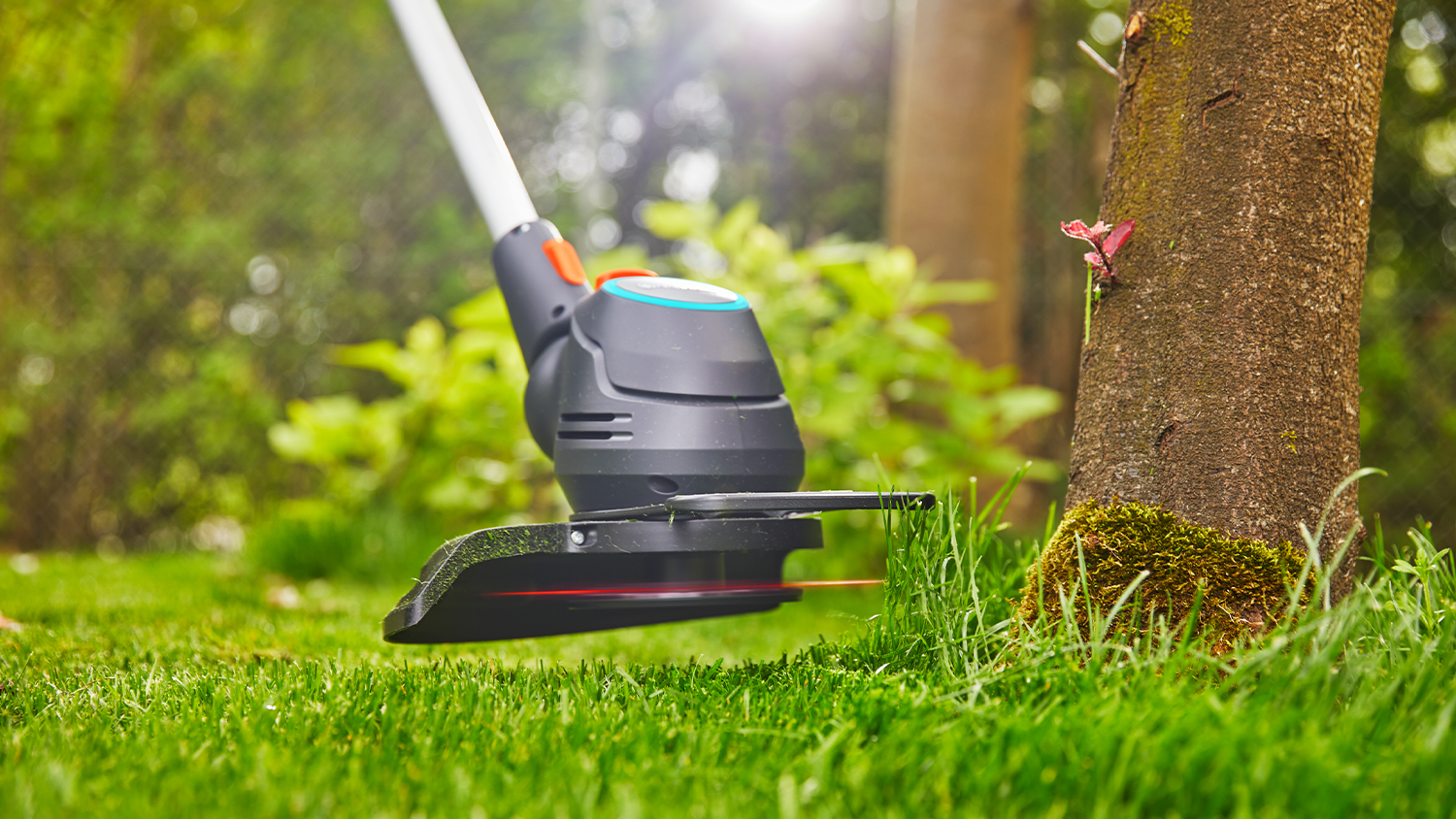 Vyžínač Gardena zastřihává trávu okolo stromu