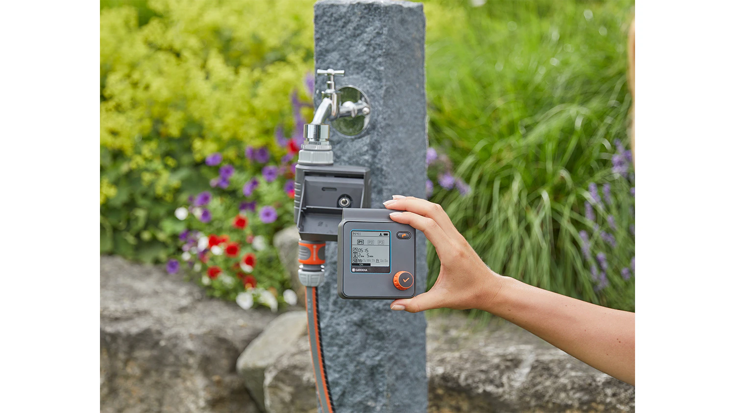 Ženská ruka drží zavlažovací počítač GARDENA Select