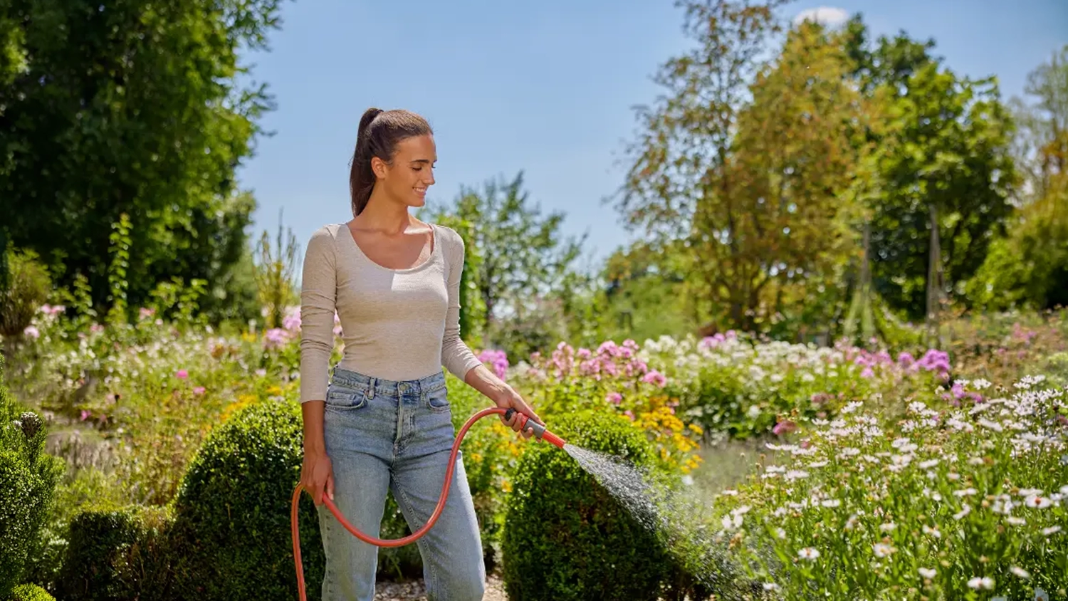 Žena zal&eacute;v&aacute; květiny soupravou GARDENA